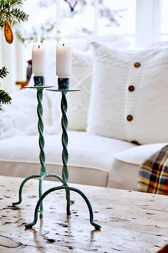 Two patina candlesticks in cozy home decor for Christmas on coffee table.