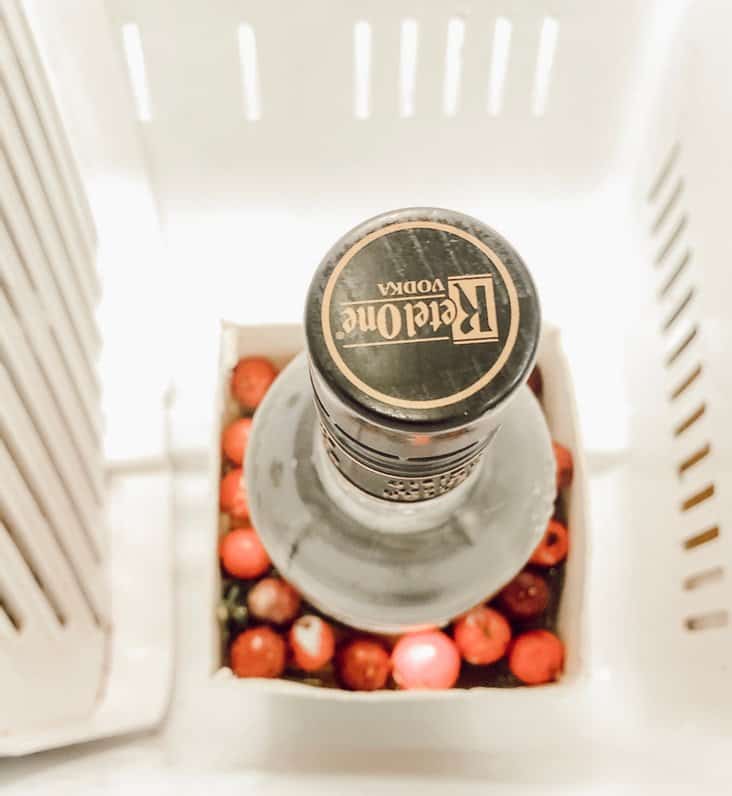 Bottle of alcohol in cart of berries and water in freezer.