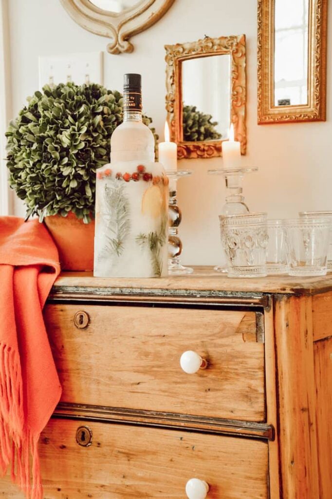 Vintage wooden dresser displaying a gorgeous DIY Ice Bucket with vintage glassware for the holidays.