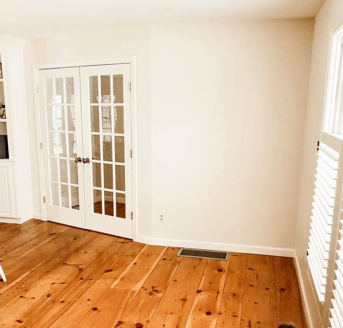 Sherwin Williams Navajo White walls in room with pine wood floors.