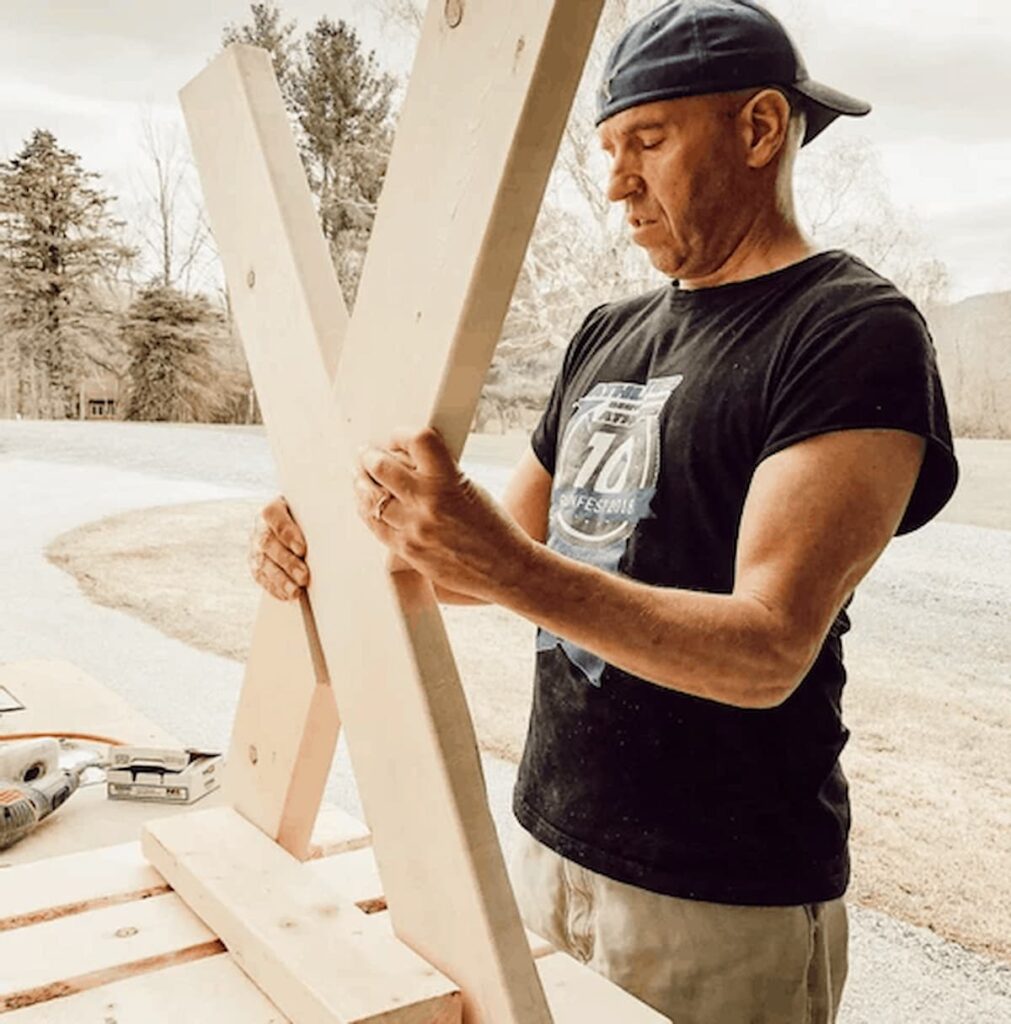 Man holding two boards together creating table legs for diy garden table.