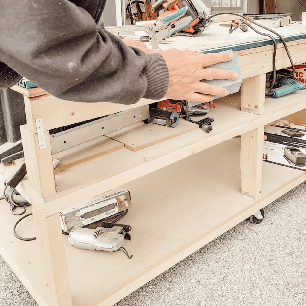 Man sanding boards for diy garden table on workbench.