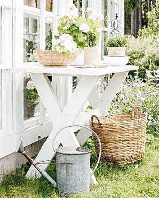 White Garden Table outdoors with baskets, watering can and white flowers for spring.