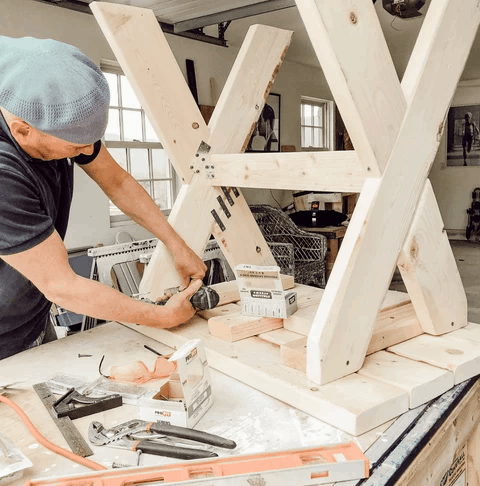 Man bolting plates onto diy garden table legs.