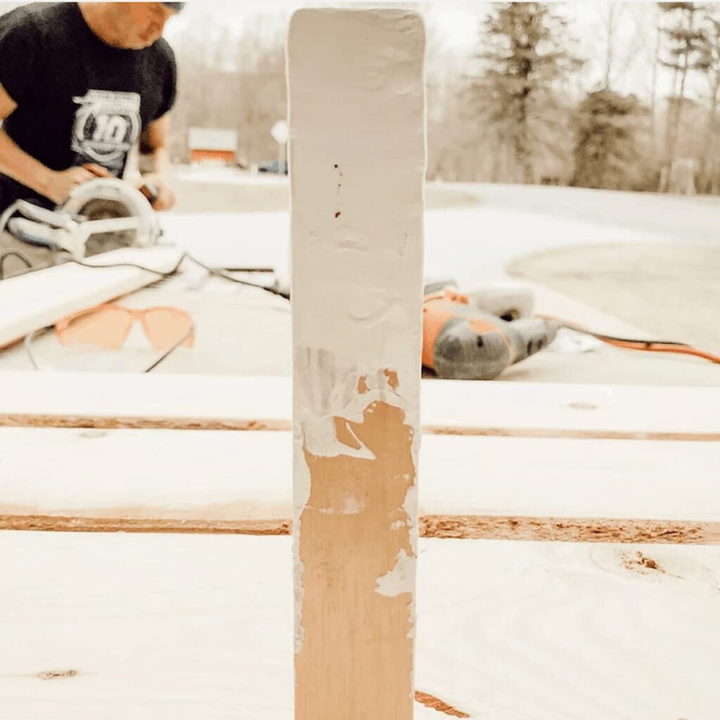 Man sanding wooden boards on workbench outdoors.