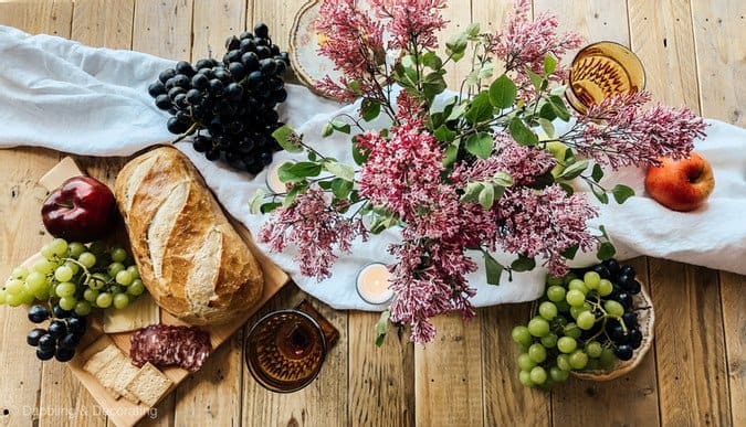 Picnic set up with breadboard and fruits on picnic table.