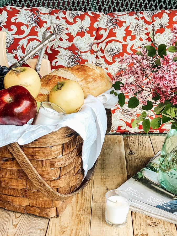 Picnic set up with vintage picnic basket filled with fruits on pallet picnic table.