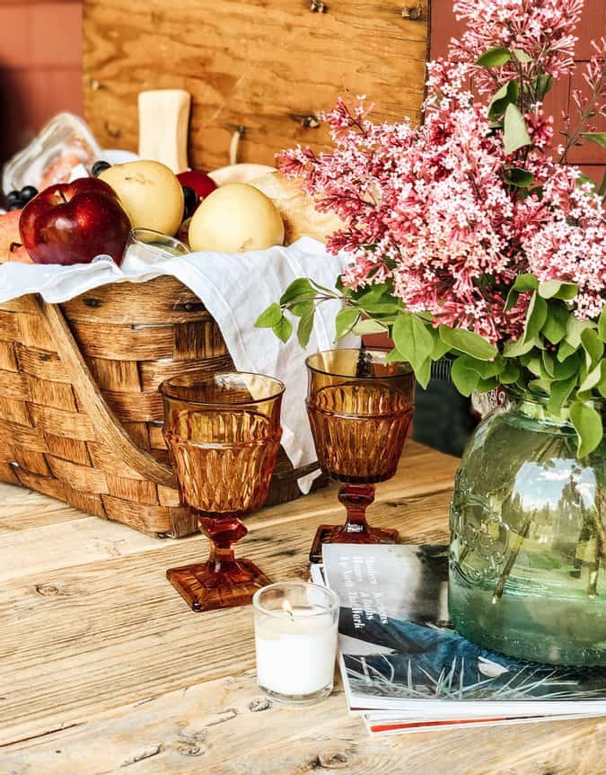 Vintage picnic basket with fruit and colored vintage glassware.