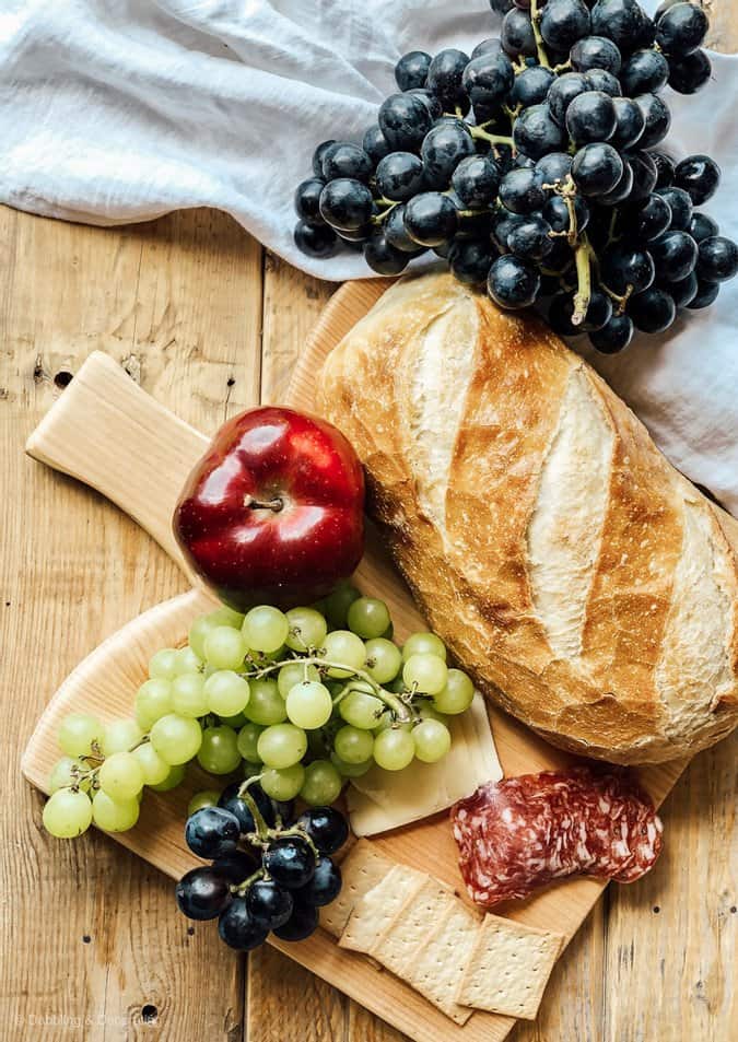 DIY breadboard with french bread, apple, and grapes for picnic set up.