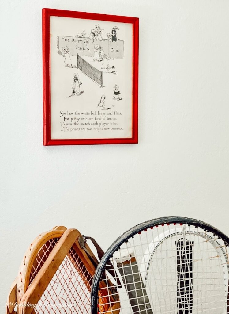 Vintage picture with cats playing tennis over basket of vintage tennis rackets.
