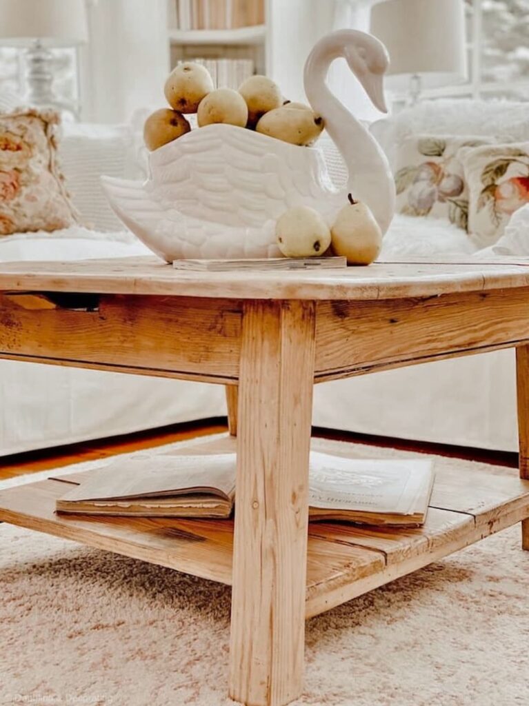 Winter White ceramic swan on wooden coffee table filled with pears in winter white sunroom.