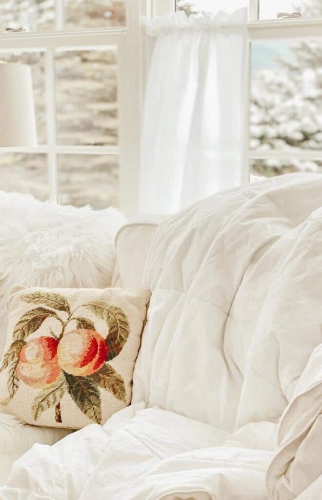 Winter White decorations in sunroom with embroidery pillow and white comforter and soft white curtains panel.