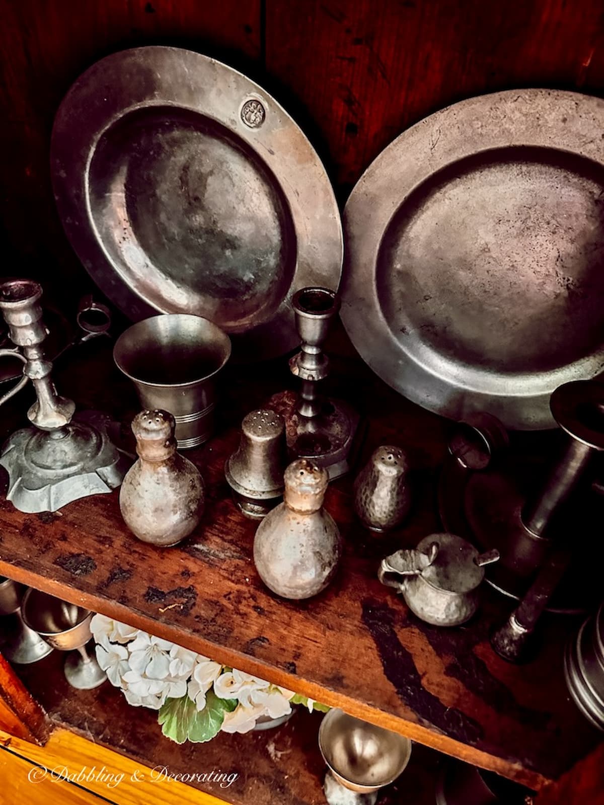 Antique American pewter collection in antique wooden hutch.