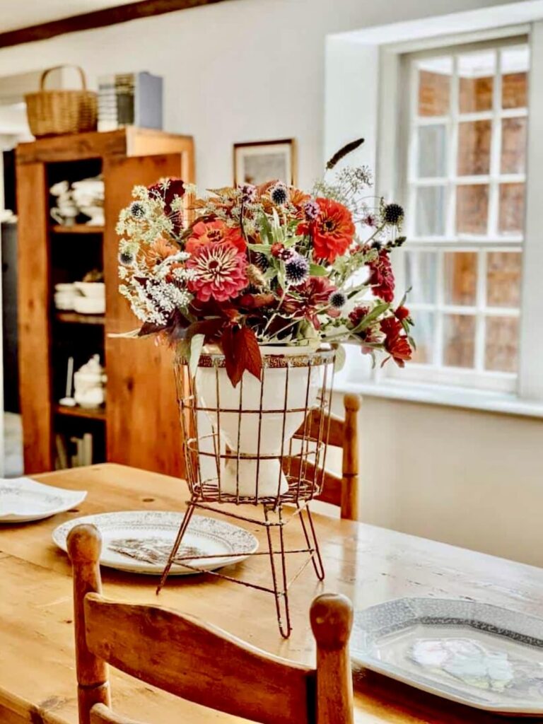 Vintage centerpiece with colorful flowers on antique table in dining room