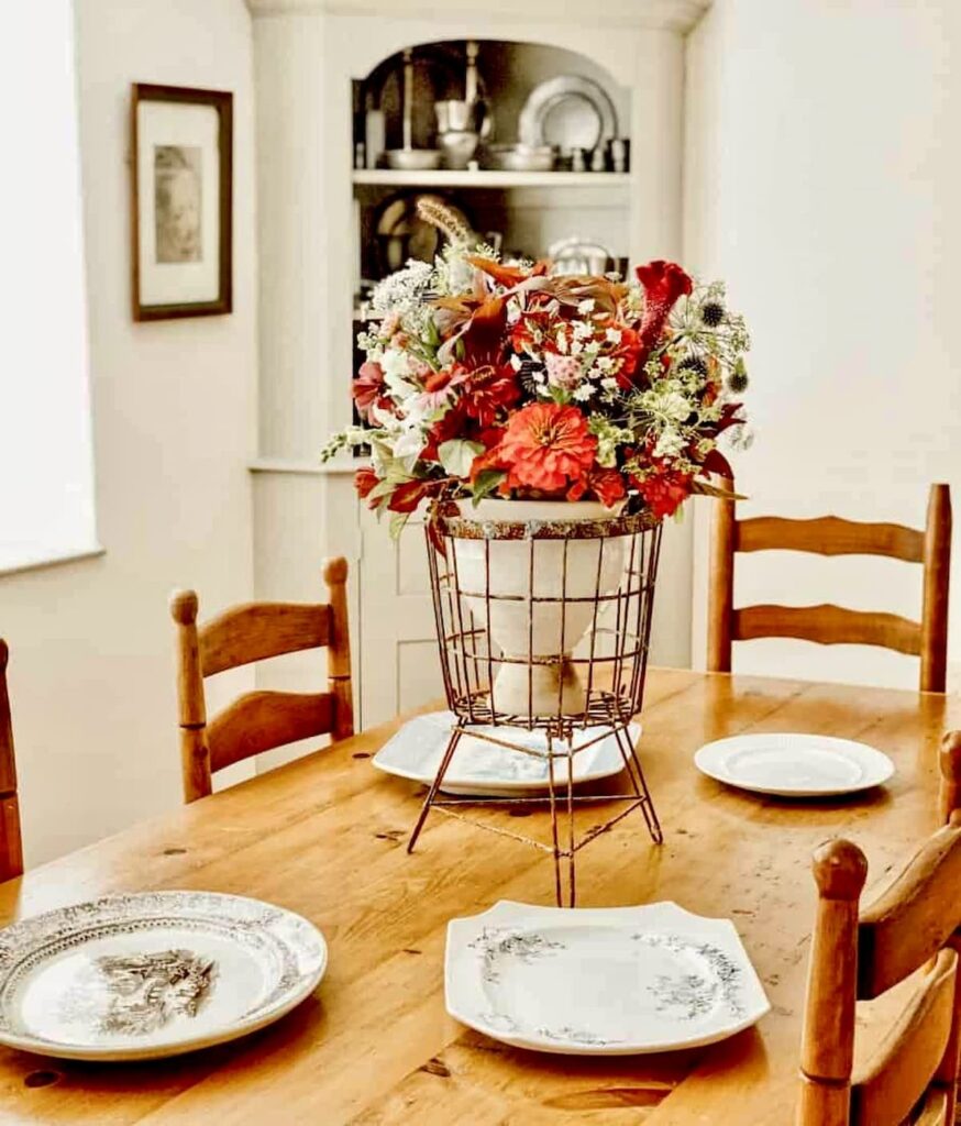 Vintage centerpiece on antique table with colorful flowers and antique platters.