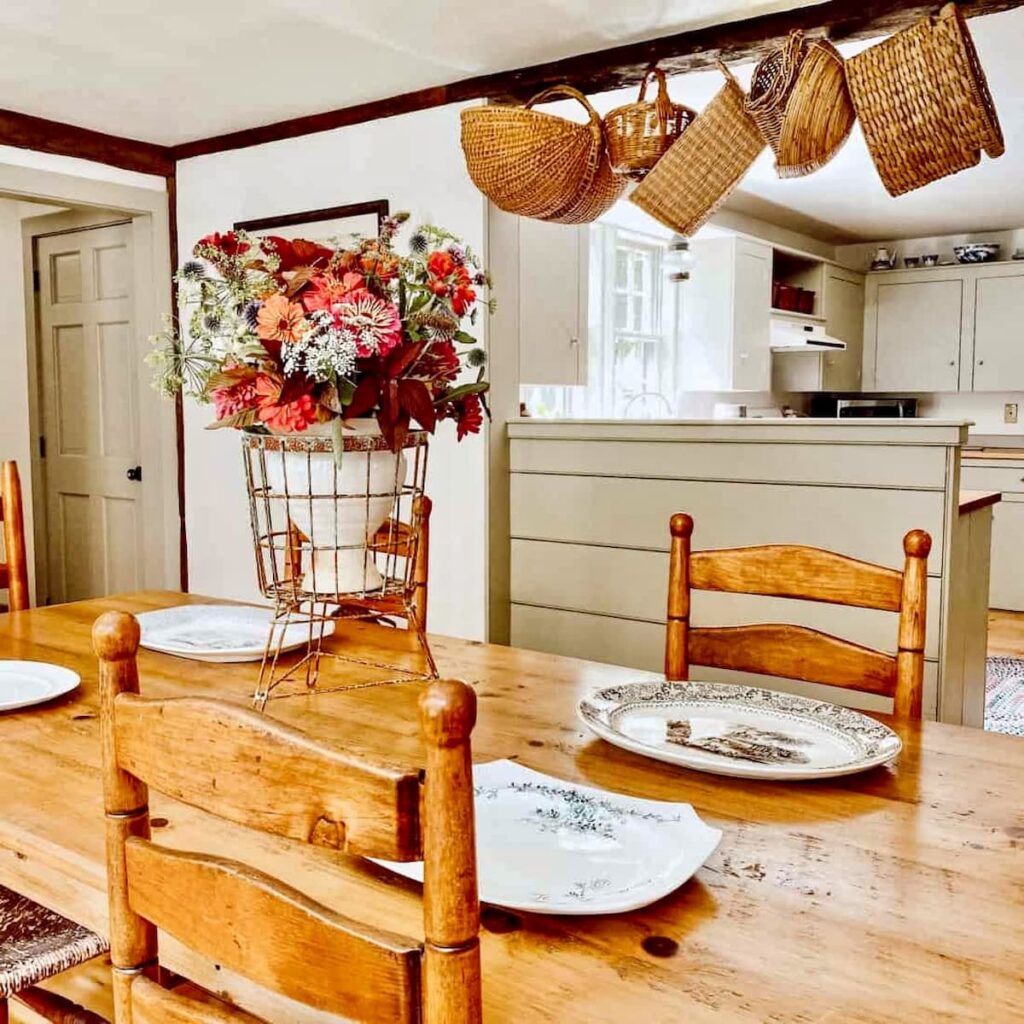 Vintage centerpiece on antique table in dining room.  Baskets hanging and platters on table.