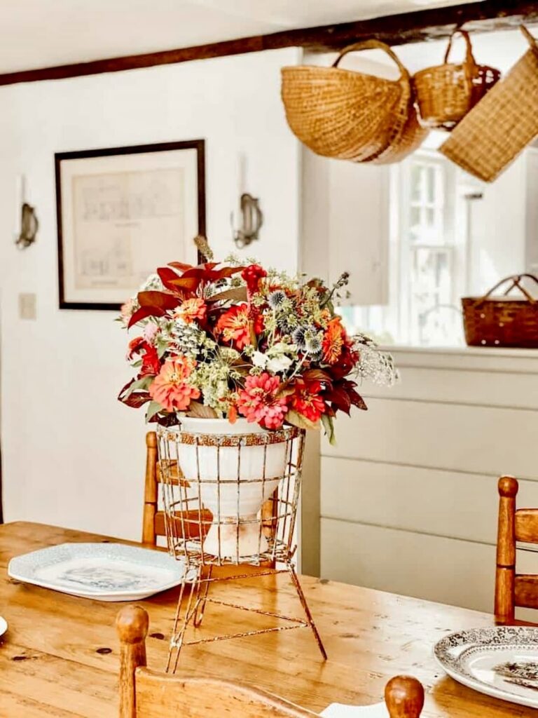 Vintage centerpiece on dining room table with hanging baskets and vintage platters.