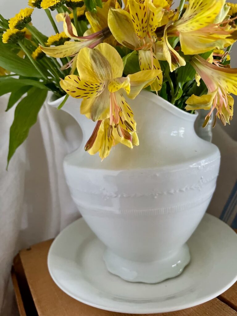 Yellow flowers in white ironstone pitcher with platter.