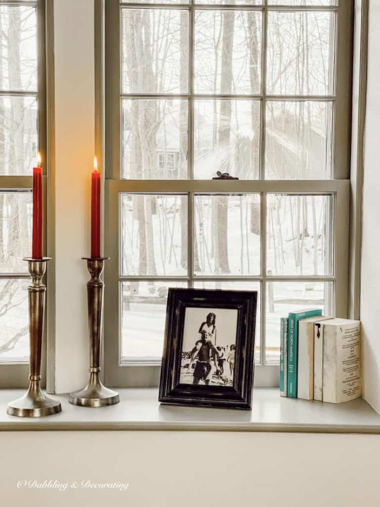 A vintage window sill with candles and books on it, creating a thrifty and charming home decor.