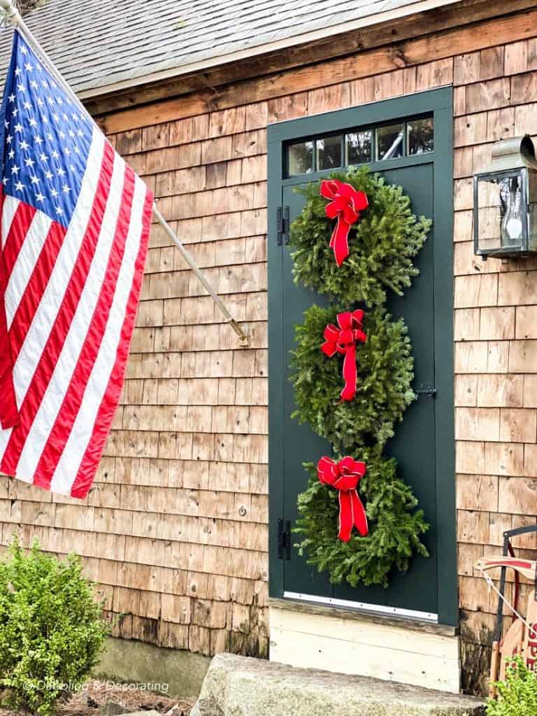 Three vintage Christmas wreaths decorating the front door of a house.