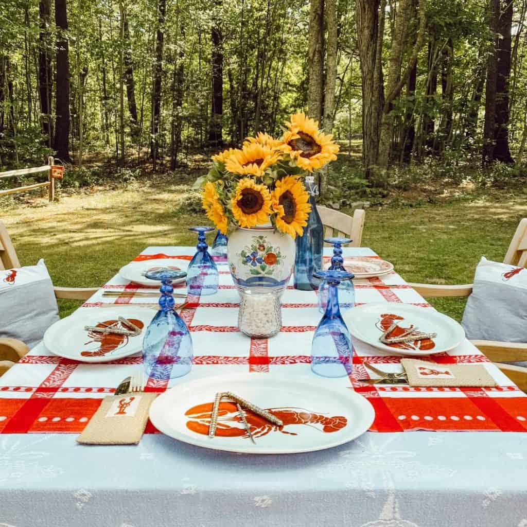 A table setting with a red, white and blue checkered tablecloth and sunflowers, perfect for home decor.