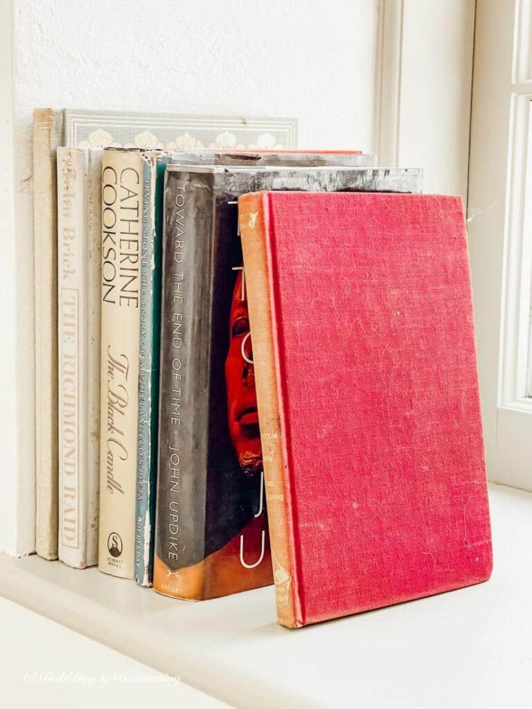 Vintage books in different colors leaning on windowsill decor.