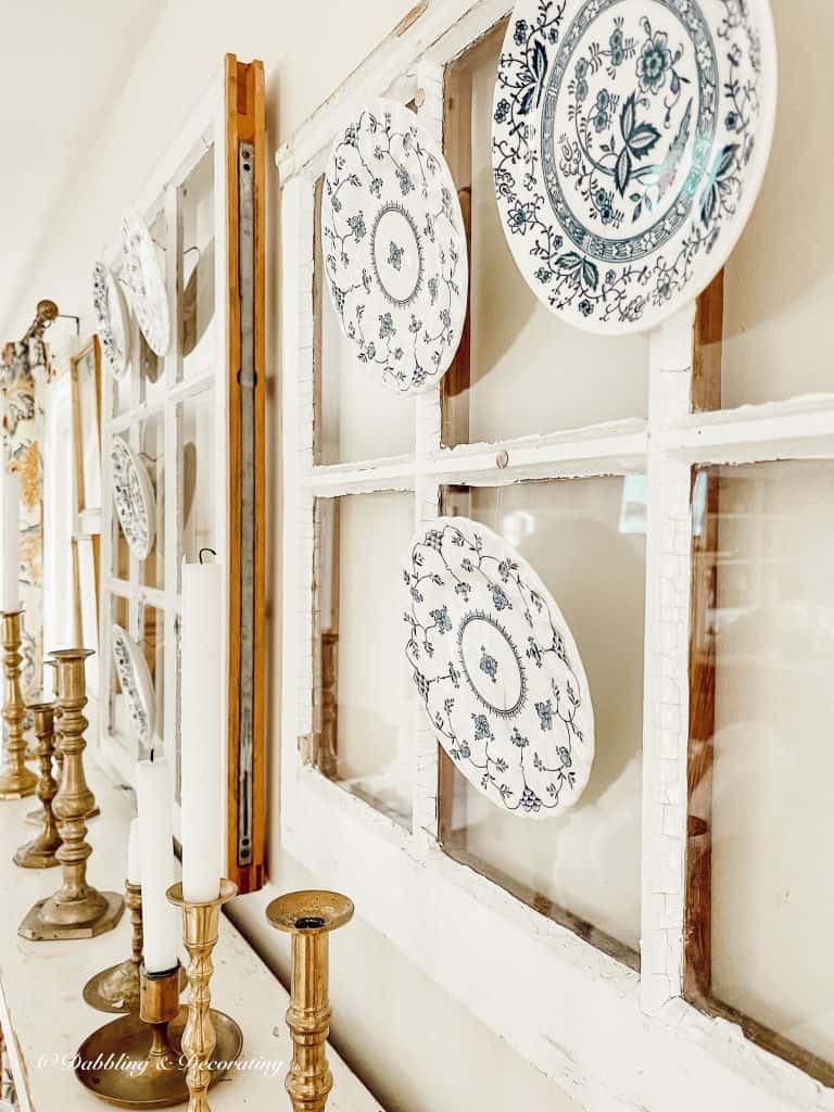 Blue and white small plates hanging on salvaged windows over mantel as wall hanging.