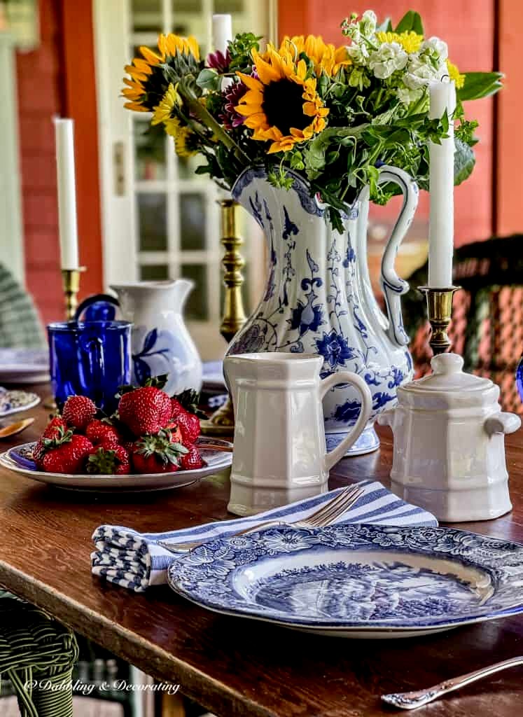 Blue and white close up of table setting on wooden wallpaper table on porch.