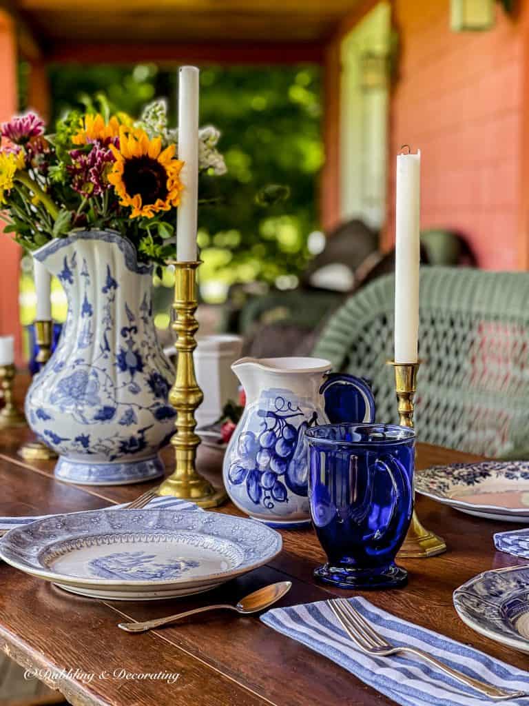 Blue and white table setting on wooden vintage wallpaper table on outdoor porch.