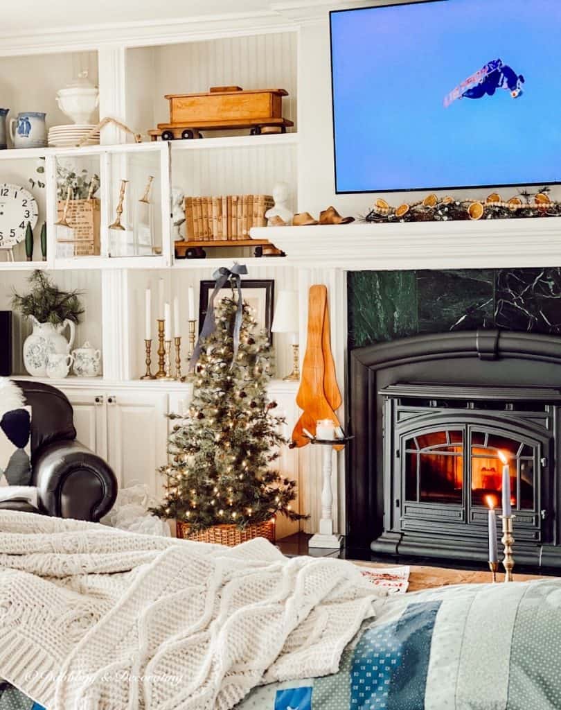 Cozy ski lodge fireplace in Christmas decorated small living room with Dear Rider Ski Movie on TV.