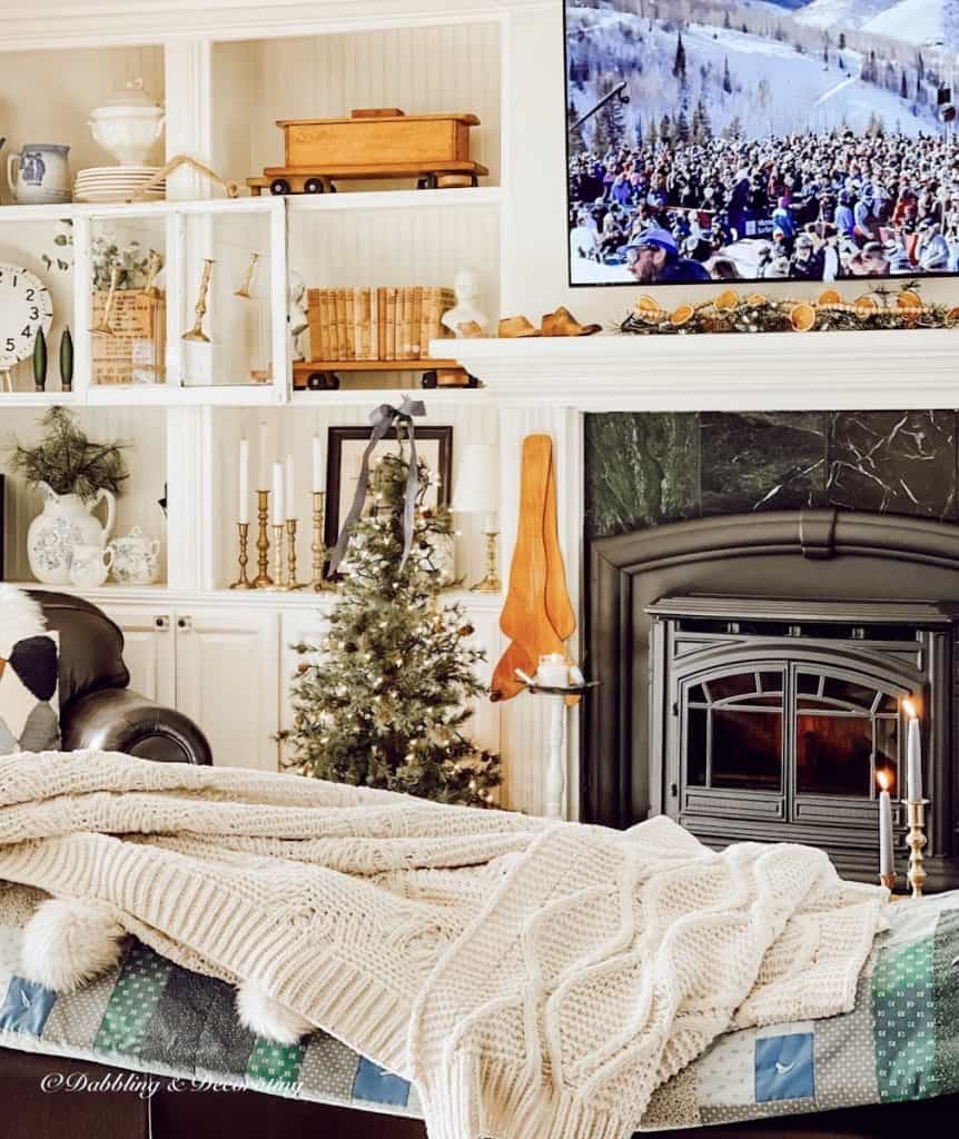 Ski lodge fireplace with pellet stove and cozy Christmas decorations with ski movie on TV.