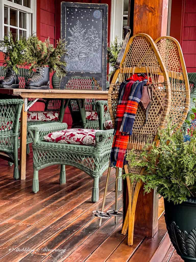 Vintage snowshoes with red scarf on ski house decor styled winter porch.