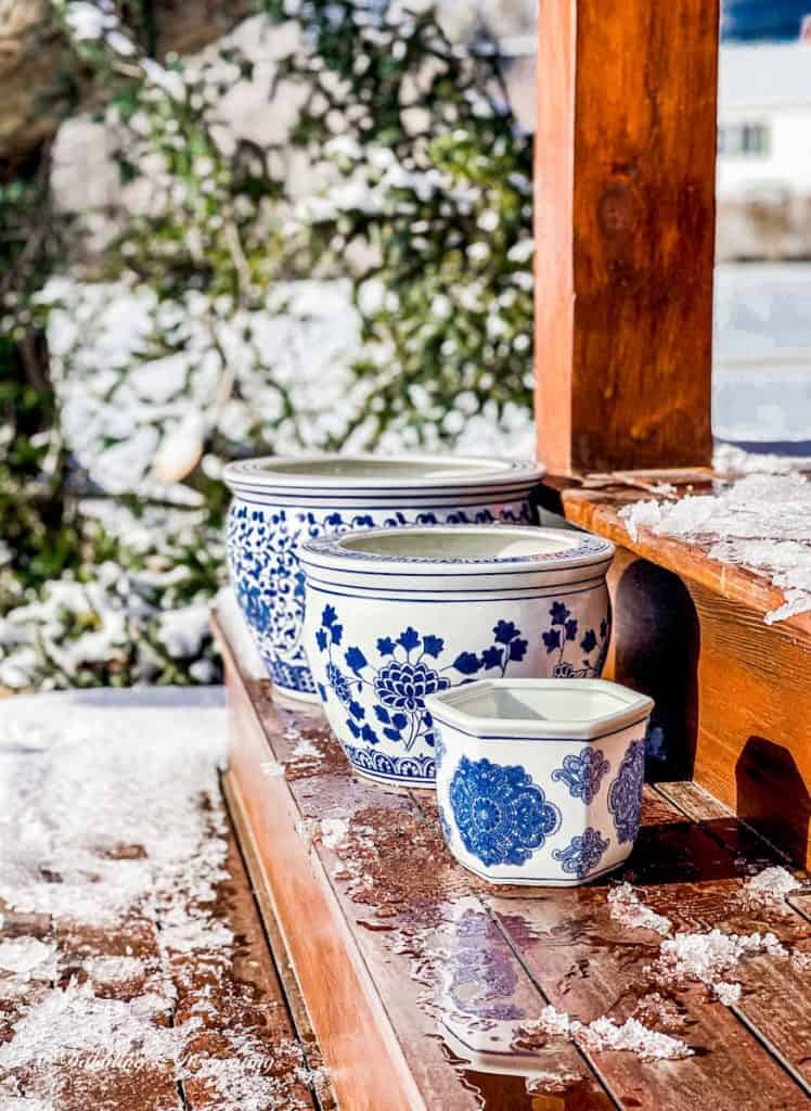 3 Blue Chinoiserie pots resting on ski house porch steps in ice and snow.