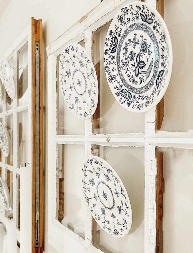 Vintage blue and white small plates hanging on a salvaged window on the wall.