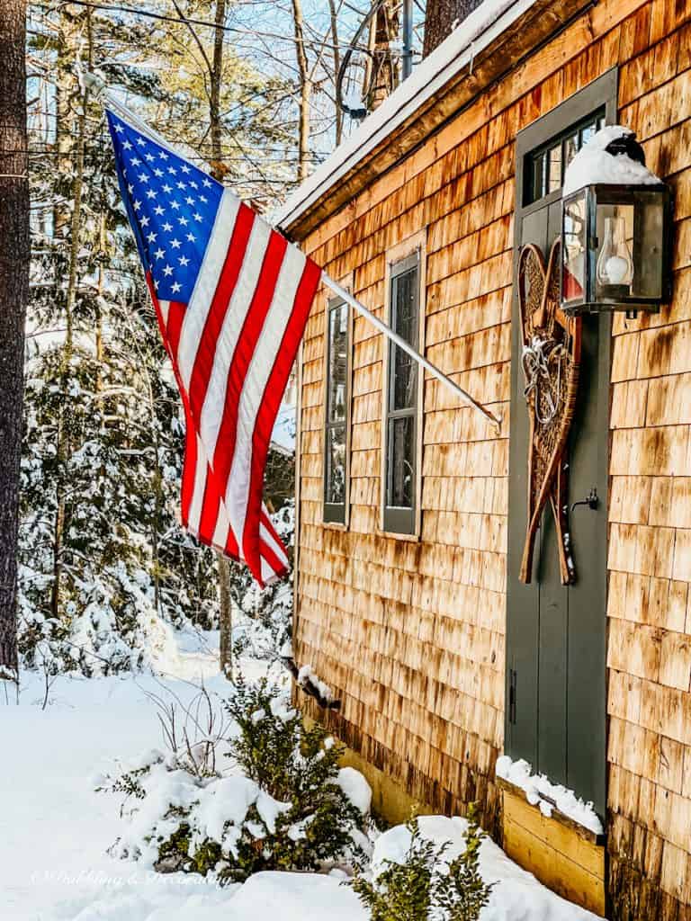 Side view of cedar shake rustic home with American Flag in the snow.