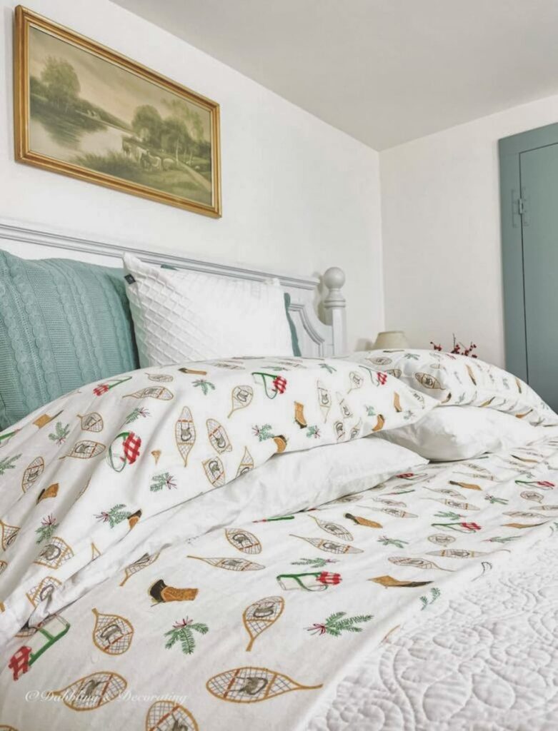 Bed with Sarah Fitz winter flannel sheets with iconic pattern of LL Bean boots, snowshoes and evergreens.