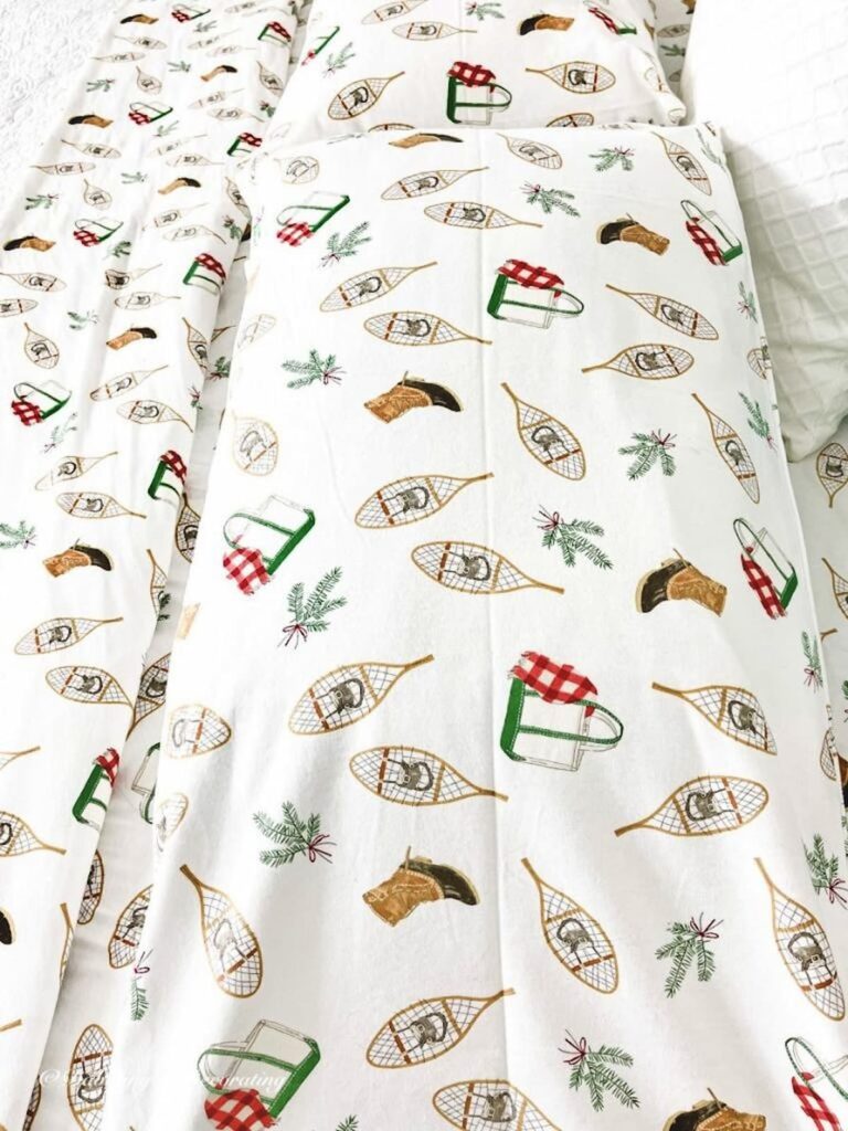 Flannel sheets by Sara Fitz with snowshoes, LL Bean boots, bags, and evergreens.  Cozy bedding collection.