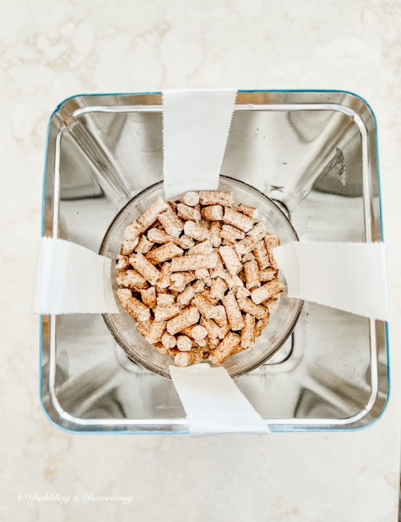 Tin with cup of pellets inside taped down in water.