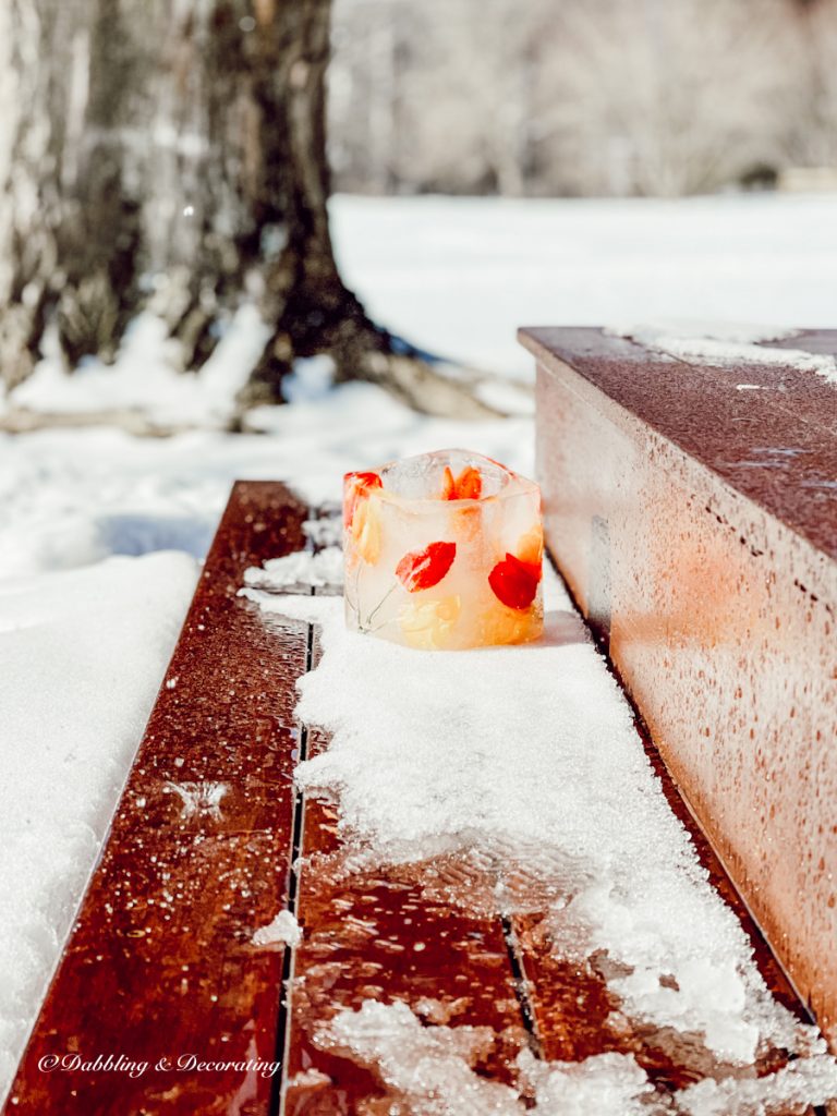 Ice candle in snow on porch front step.