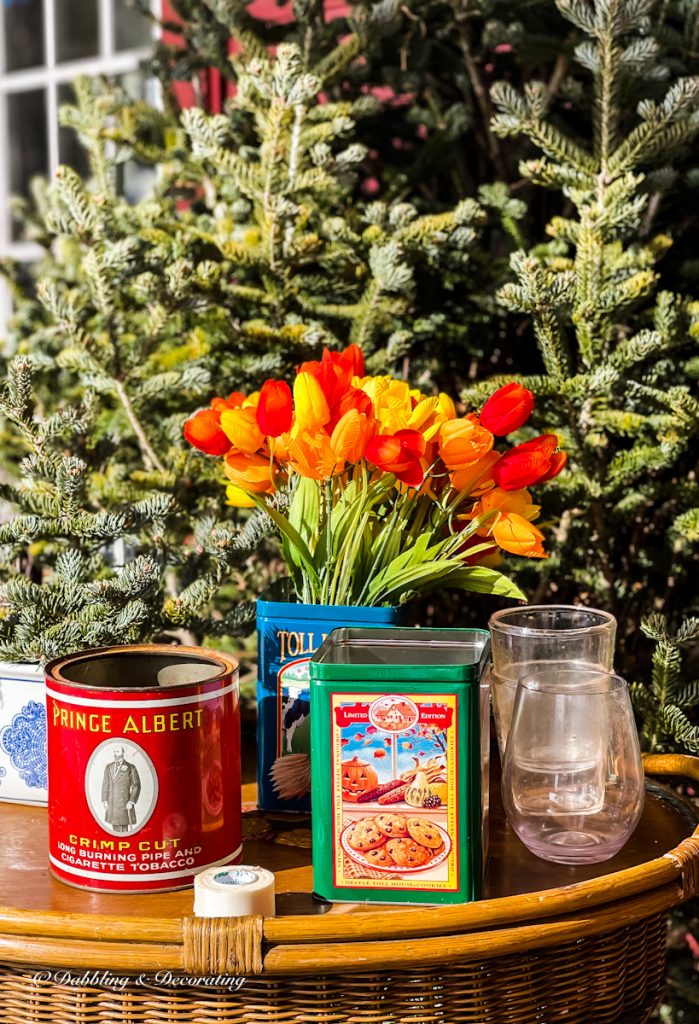 Three tin cans, faux tulips in orange and red, plastic cups for winter lantern ice tutorial.