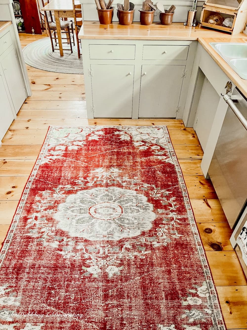A vintage kitchen with a red rug on the floor.
