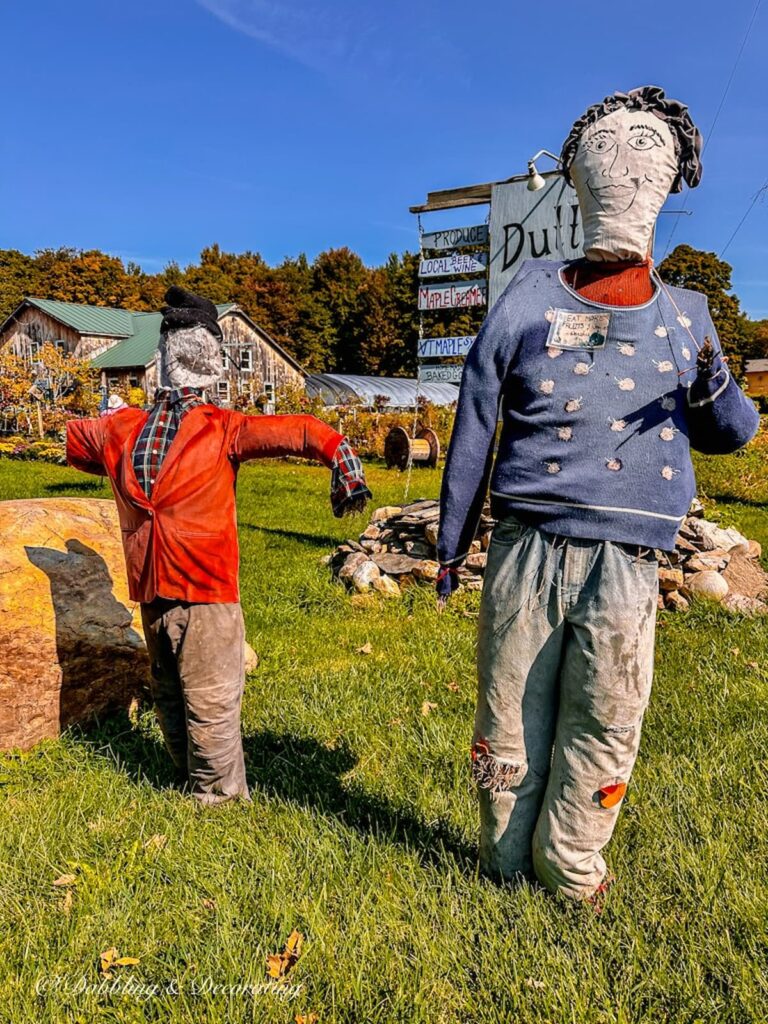 Two scarecrows with name tag that says East More Fruits and Vegetables.