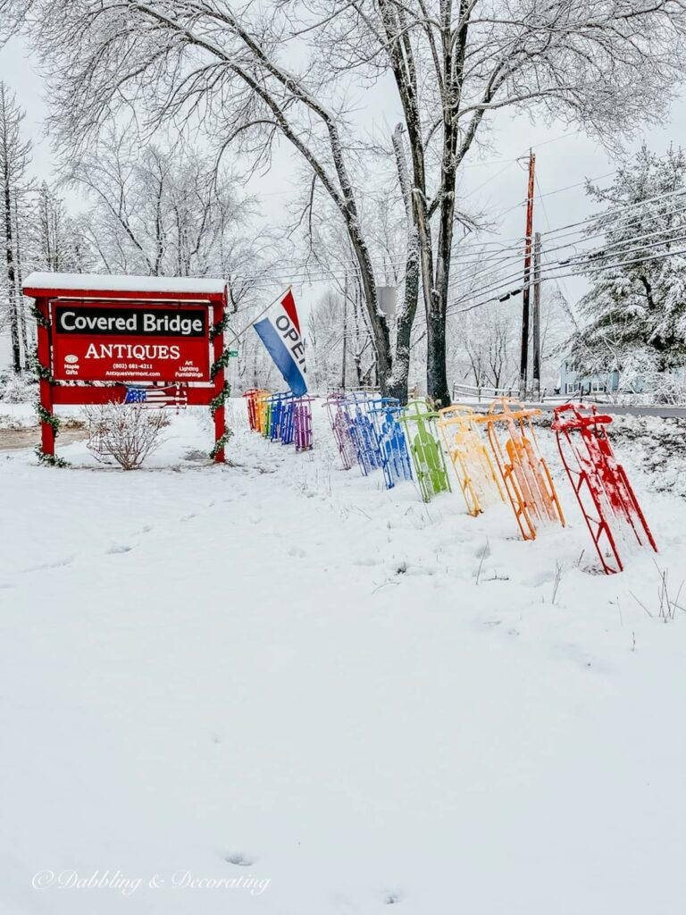 The Covered Bridge Antique in snow with colorful vintage sleds.