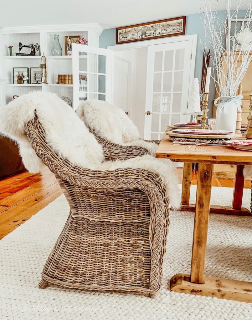 Vintage Nordic table on white braided rug with wicker chairs in dining room space.