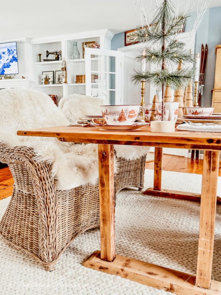 Vintage pine table in dining room cozy with white braided rug and wicker chairs with sheepskins in dining room.