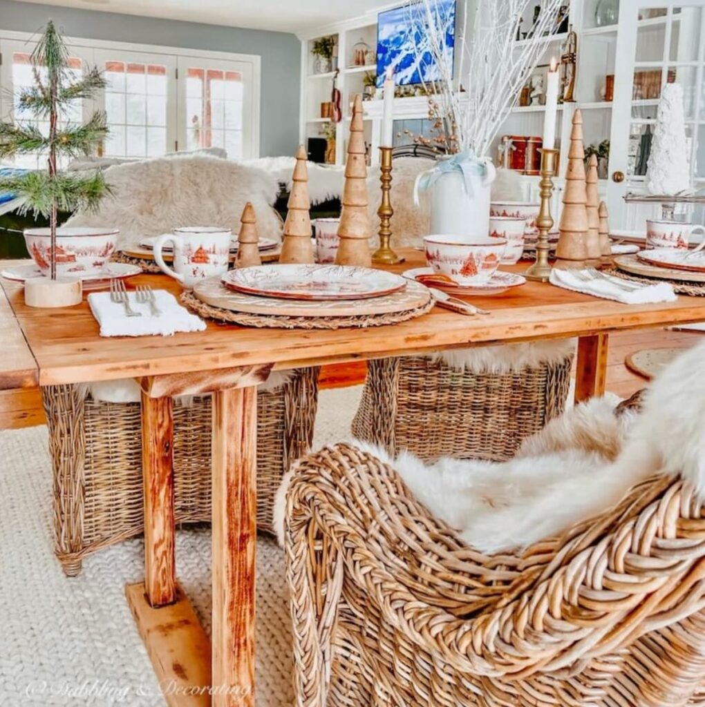 Vintage wooden table in Vermont home's dining room with wicker chairs and sheepskins with television playing Dear Rider in the background.