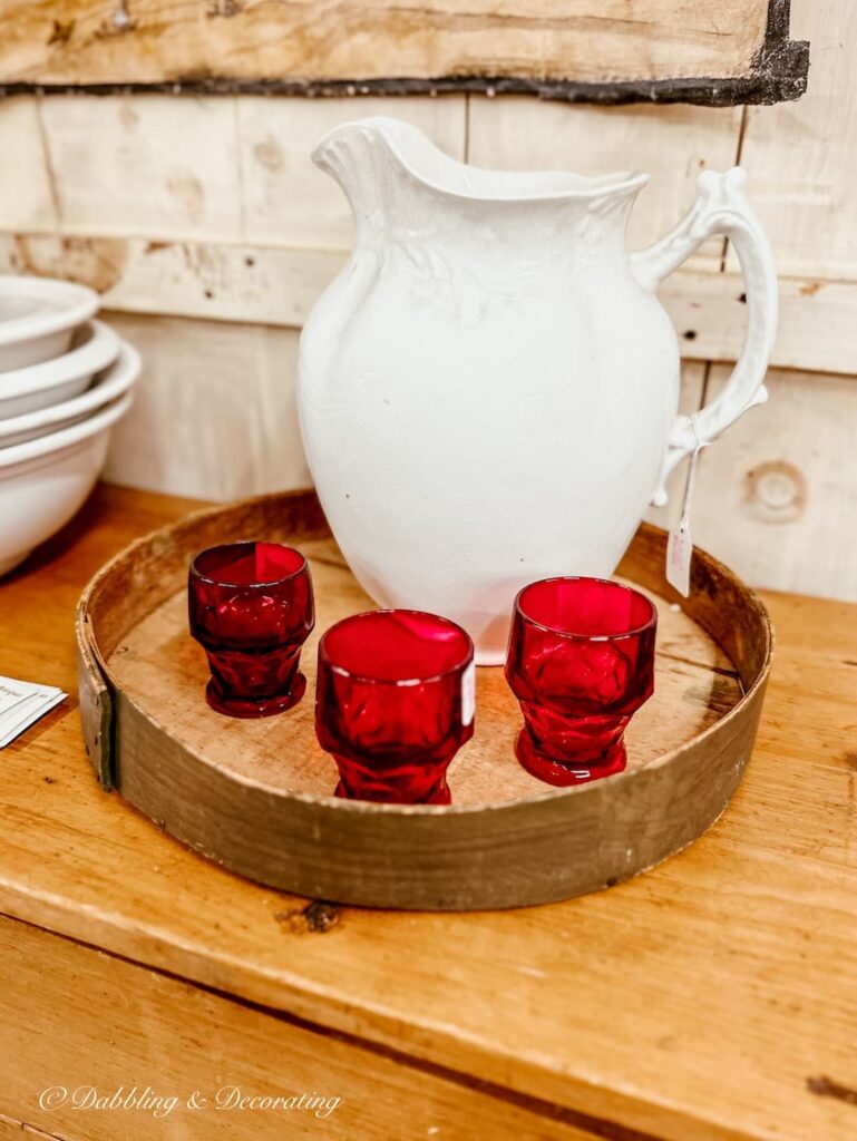 Vintage white pitcher with red glasses on a vintage wooden tray for Valentines Day