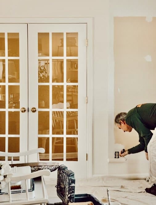 Man painting a living room interior with Navajo White Paint.