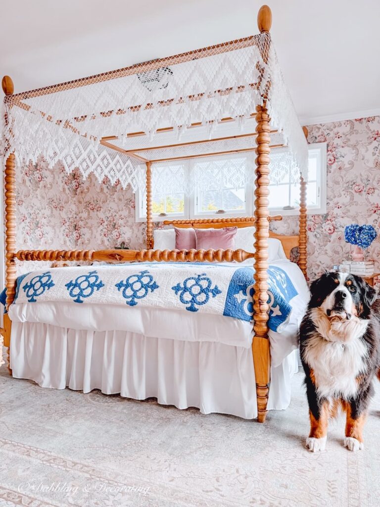 Canopy bed in wallpapered master bedroom with Bernese Mountain Dog looking on.