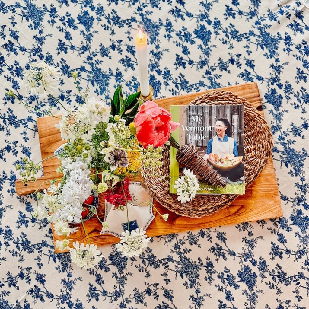 Vintage Cutting boards as table centerpiece on blue and white table cloth with book and flowers.